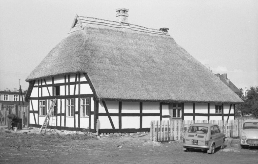 Gotowy budynek skansenowy z dachem ze strzechy i konstrukcją ryglową, widok z zewnątrz podczas końcowego etapu prac (kliknięcie powiększy zdjęcie)