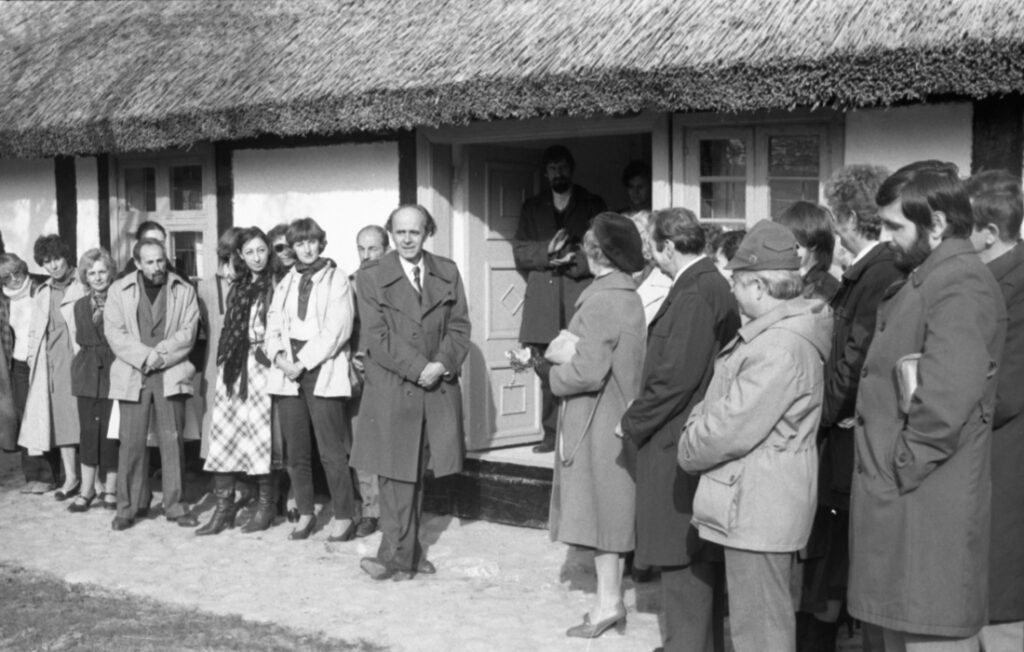 Grupa zaproszonych gości stojących przed wejściem do budynku skansenu, oficjalna część uroczystości otwarcia (kliknięcie powiększy zdjęcie)
