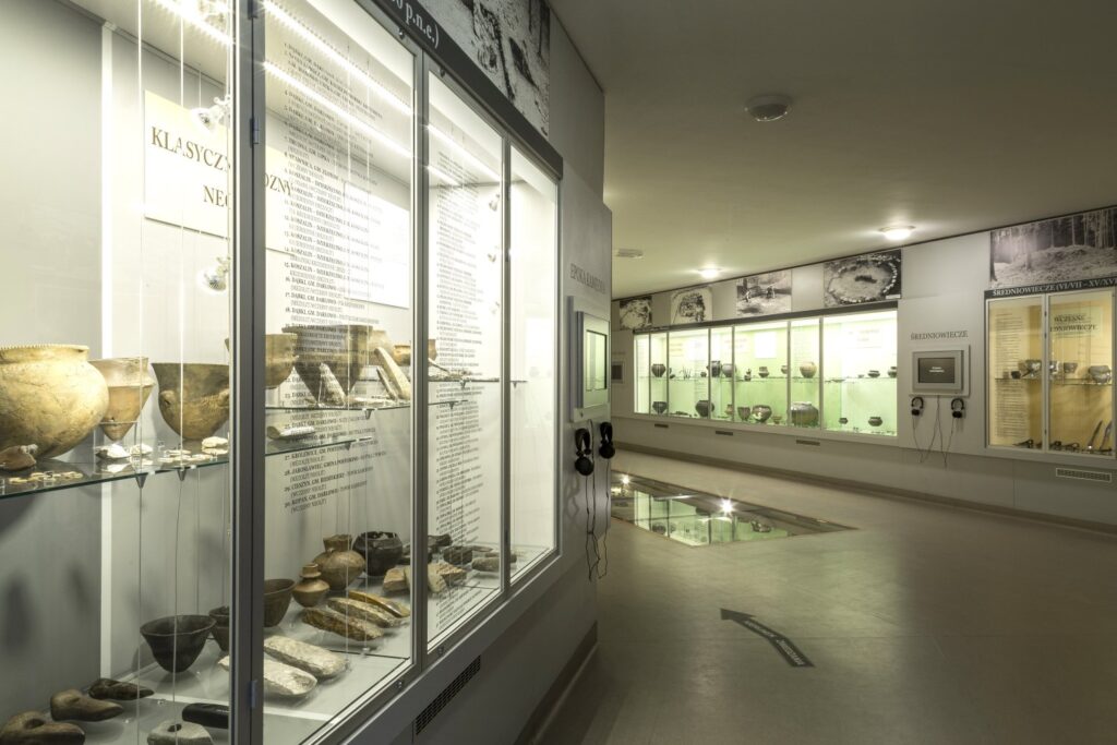 Widok ciągu gablot i plansz informacyjnych na wystawie archeologicznej „Pradzieje Pomorza”, prezentujących zabytki ceramiczne i kamienne (kliknięcie powiększy zdjęcie)