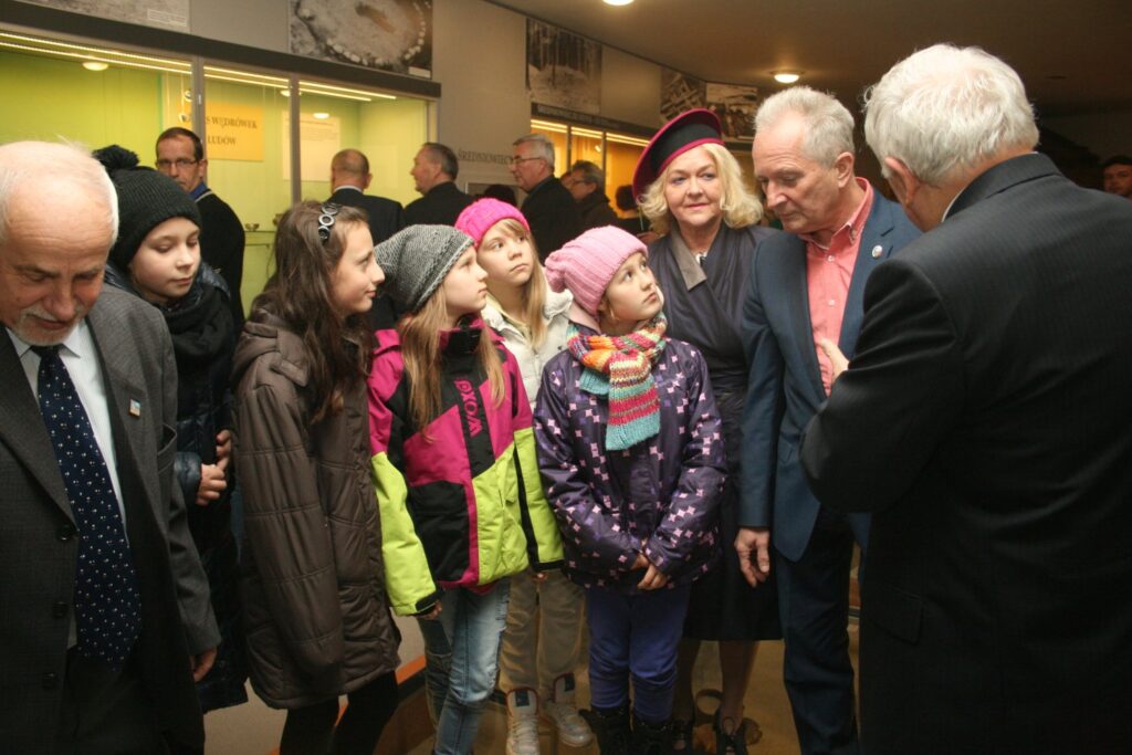 Dzieci i dorośli oglądający eksponaty w gablocie, wspólne zwiedzanie wystawy muzealnej (kliknięcie powiększy zdjęcie)