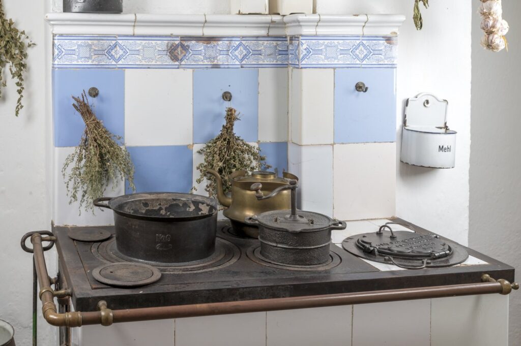 Wnętrze kuchni w chałupie – tradycyjny piec kuchenny z żeliwnymi naczyniami i suszonymi ziołami zawieszonymi nad paleniskiem (kliknięcie powiększy zdjęcie).