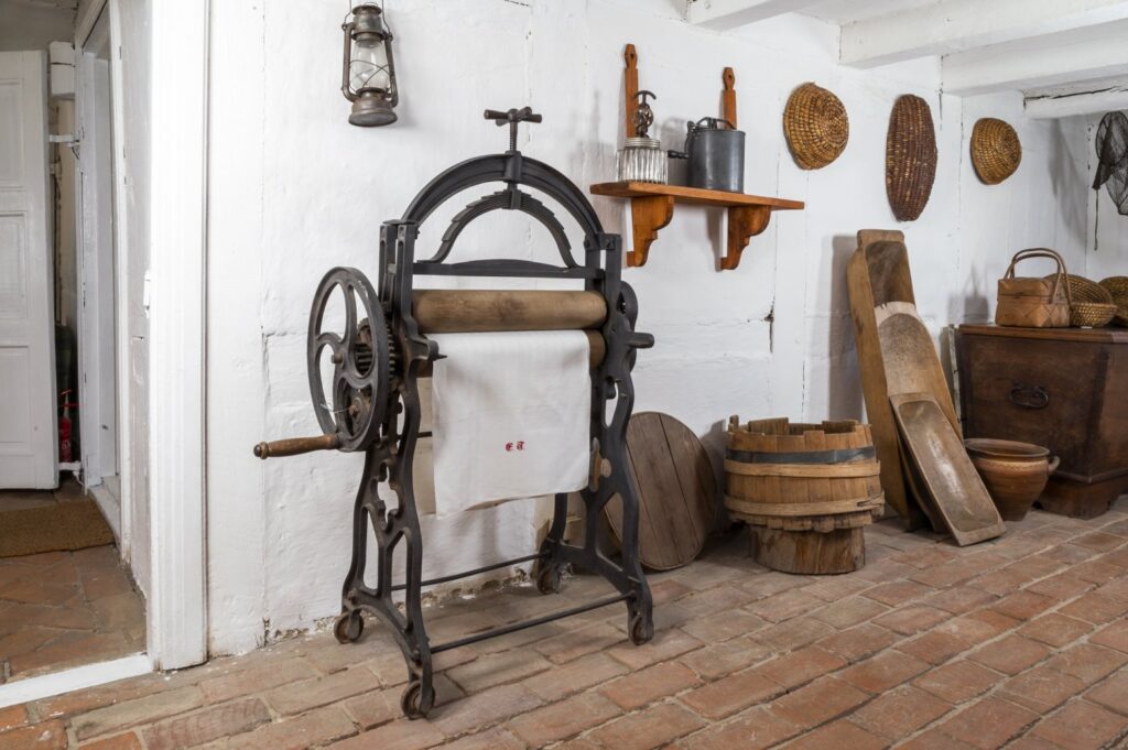 Zabytkowa maglownica ręczna oraz sprzęty gospodarcze ustawione w sieni chałupy rybackiej (kliknięcie powiększy zdjęcie).