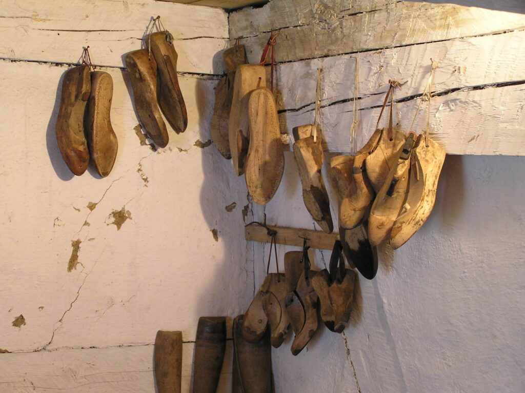 Drewniane kopyta szewskie zawieszone na ścianie warsztatu, używane do formowania obuwia (kliknięcie powiększy zdjęcie).