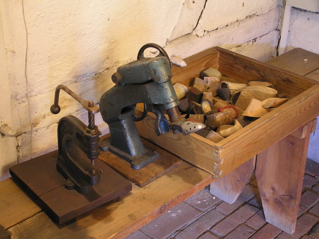 Ręczna maszyna szewska oraz skrzynka z drewnianymi kopytami i narzędziami używanymi do produkcji obuwia (kliknięcie powiększy zdjęcie).