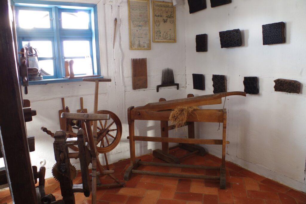 Ekspozycja narzędzi tkackich i elementów obróbki włókna ustawionych w muzealnym wnętrzu (kliknięcie powiększy zdjęcie).