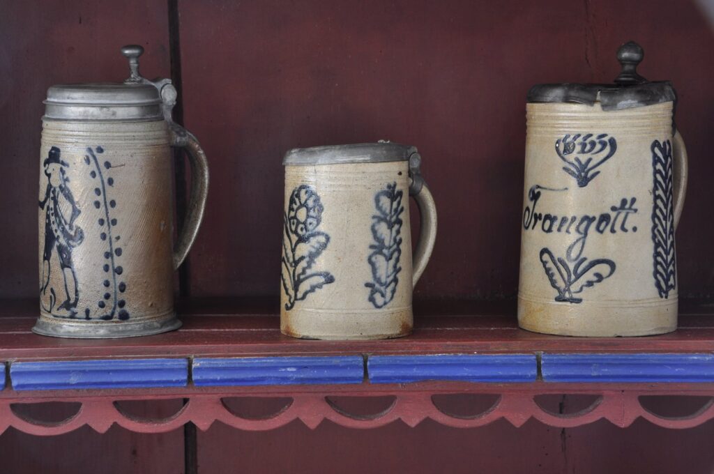 Trzy kufle z dekoracyjnymi motywami roślinnymi ustawione na półce w izbie (kliknięcie powiększy zdjęcie).