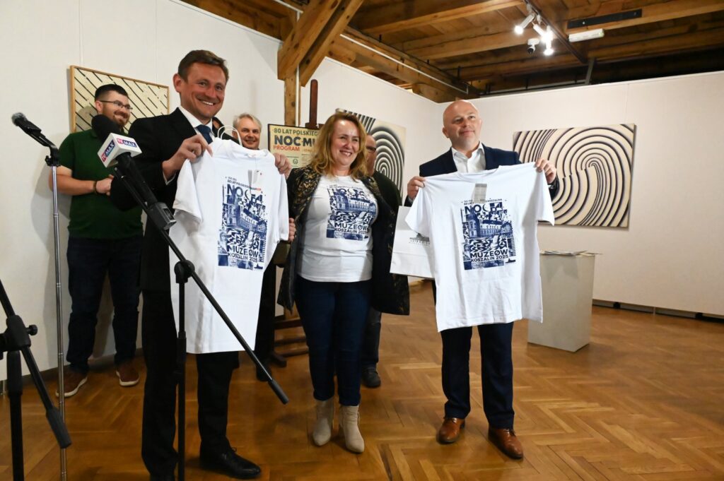 Prezydent Koszalina, Pani Dyrektor Muzeum w Koszalinie i Wiceprezydent Koszalina pokazują koszulki z nadrukami przygotowane na Noc Muzeów 2025.