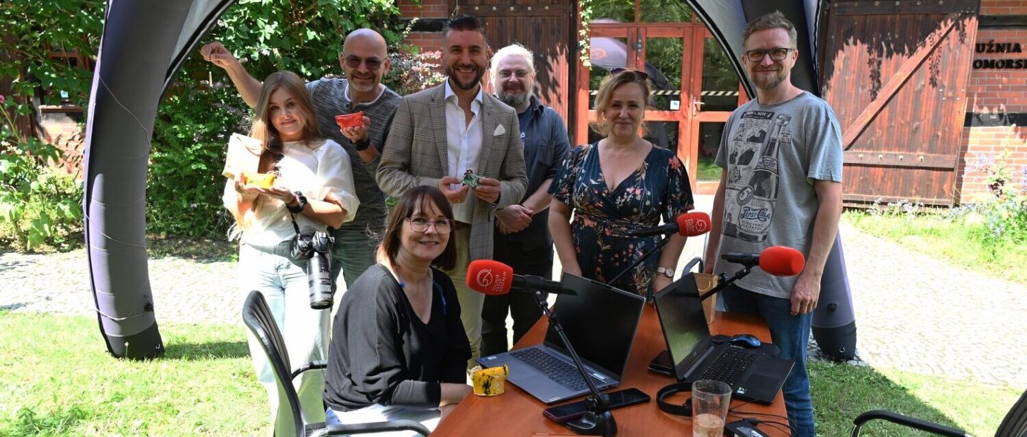 Pamiątkowe zdjęcie w studiu plenerowym Radia Koszalin. W tle budynek z wystawą "Kuźnia Pomorska".