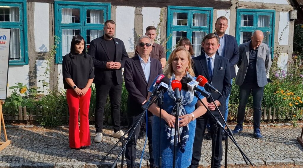 Dyrektor Muzeum w Koszalinie przemawia przed mikrofonami. Za nią stoją osoby z instytucji, które współorganizują wydarzenie (kliknięcie spowoduje powiększenie zdjęcia).