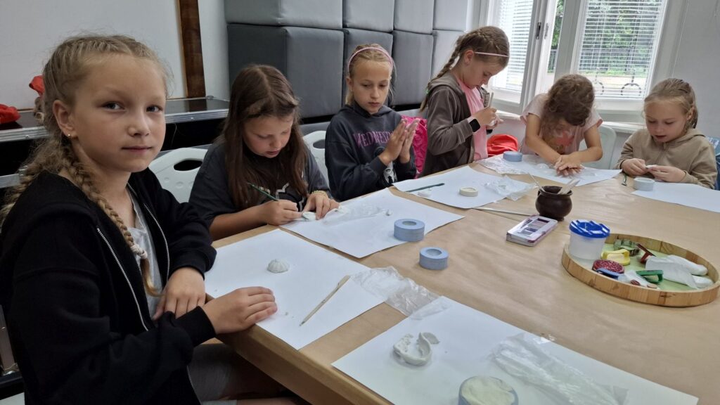 Dzieci ugniatają i malują farbkami formy, w ramach warsztatów z reliefu (kliknięcie spowoduje powiększenie zdjęcia).