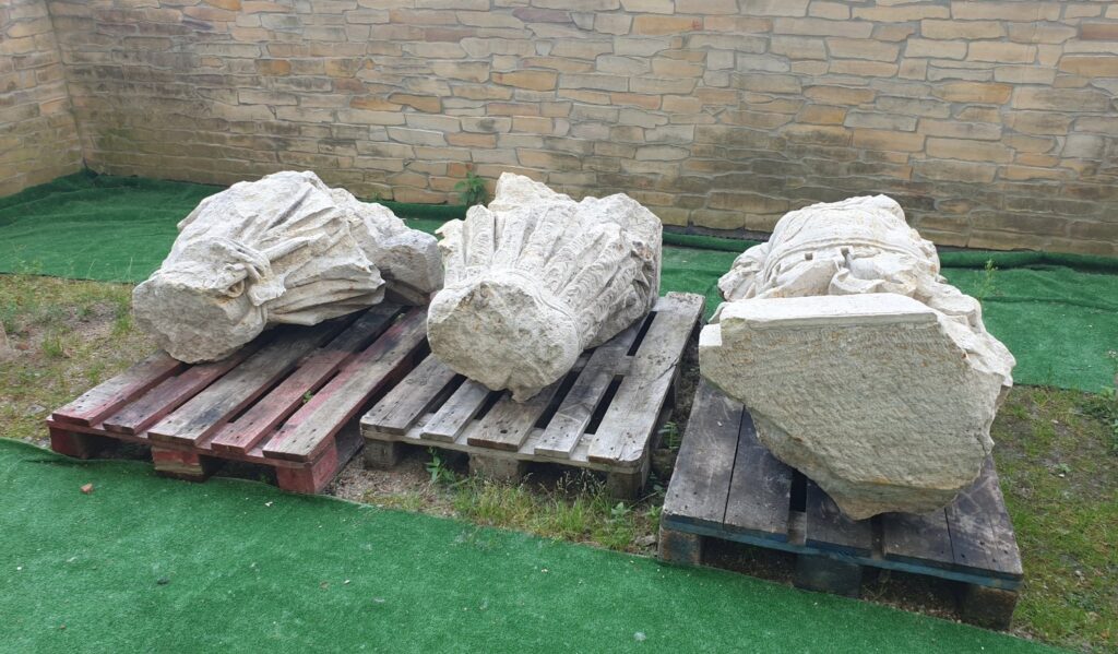 Ułożone na paletach, trzy fragmenty pomnika króla Fryderyka Wilhelma. W tle widoczny kawałek muru (kliknięcie spowoduje powiększenie zdjęcia).