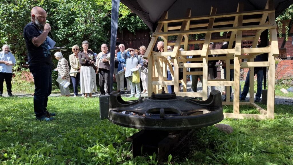 Na pierwszym planie urządzenie zwane kieratem. Obok niego stoi model szkieletu szachulcowego. W tle ludzie uczestniczący w oprowadzaniu po wystawie (kliknięcie spowoduje powiększenie zdjęcia).