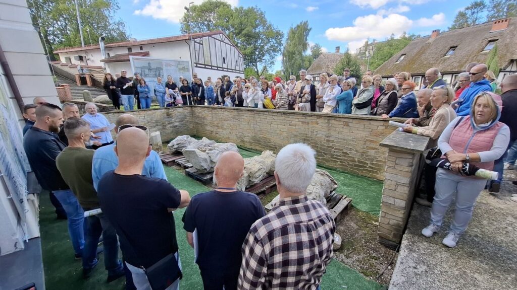 Ludzie stoją przed fosą przy budynku muzeum. W fosie znajdują się fragmenty pomnika Fryderyka Wilhelma I. W tle widoczne zabudowania muzeum (kliknięcie spowoduje powiększenie zdjęcia).
