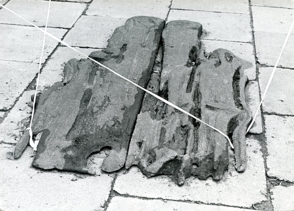 Czarno-biała fotografia fragmentów zniszczonych materiałów lub obiektów ułożonych na chodniku i przewiązanych sznurkiem (kliknięcie powiększy zdjęcie).
