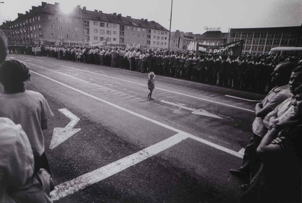 Mała dziewczynka stoi na środku ulicy, wśród ludzi zgromadzonych na manifestacji. W tle zabudowania Koszalinie (kliknięcie spowoduje powiększenie zdjęcia)