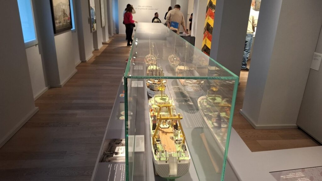 Długi korytarz muzealny z przeszklonymi gablotami zawierającymi modele i eksponaty techniczne (kliknięcie powiększy zdjęcie)