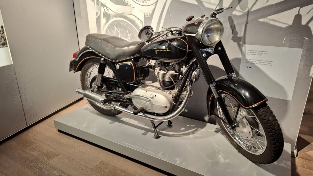 Zabytkowy motocykl wystawiony na podwyższeniu w sali muzealnej (kliknięcie powiększy zdjęcie)