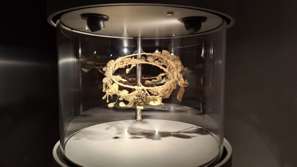 Złoty wieniec lub ozdoba historyczna prezentowana w szklanej, cylindrycznej gablocie (kliknięcie powiększy zdjęcie)