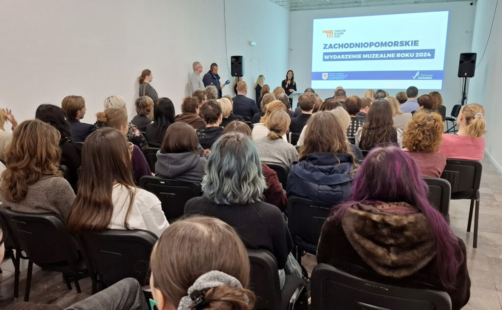 Publiczność siedzi w sali podczas gali wręczenia nagród na Zachodniopomorskie Wydarzenie Roku 2024. Na scenie stoją prelegenci, a na ekranie wyświetla się prezentacja (kliknięcie powiększy zdjęcie)