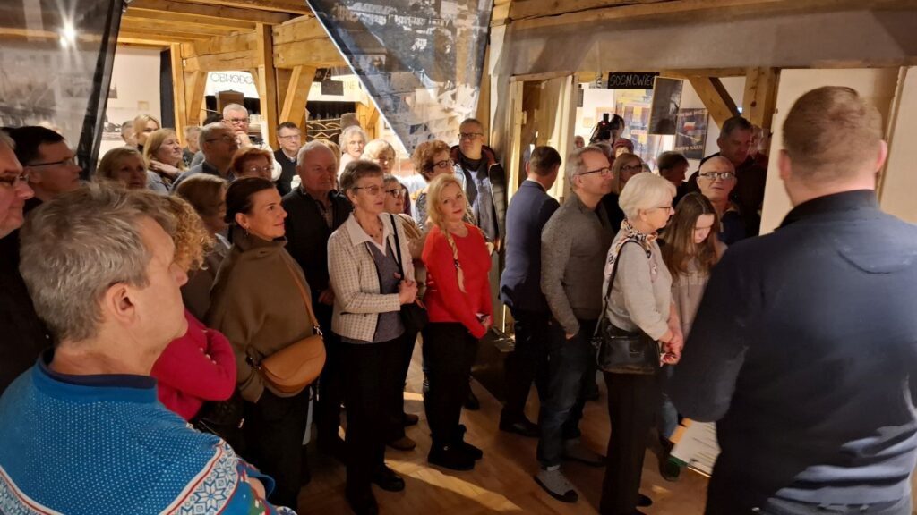 Liczna grupa zwiedzających zgromadzona wokół przewodnika w sali muzealnej (kliknięcie powiększy zdjęcie)