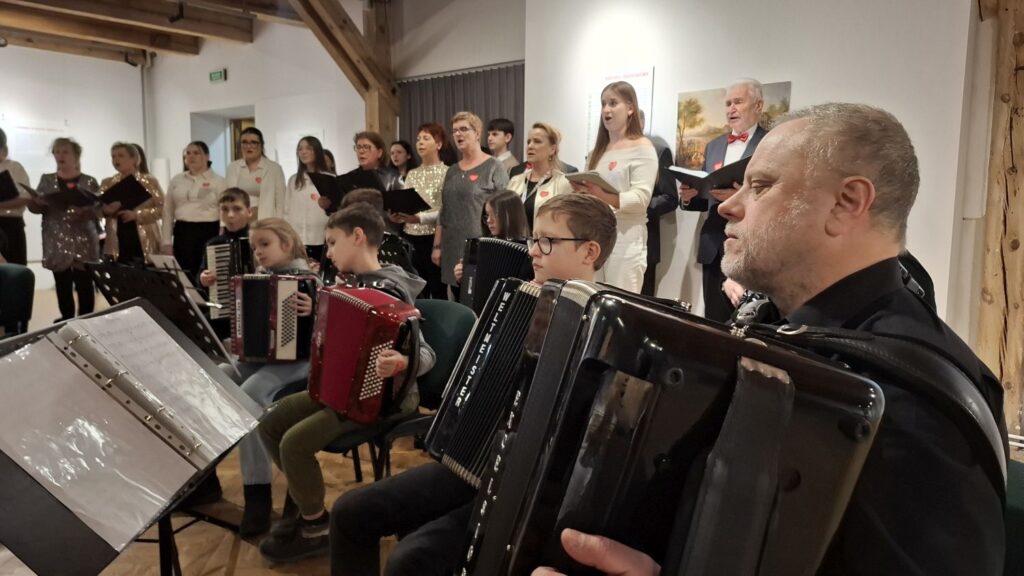 Muzycy grający na akordeonach podczas koncertu, w tle stojący chór i zgromadzona publiczność (kliknięcie powiększy zdjęcie)