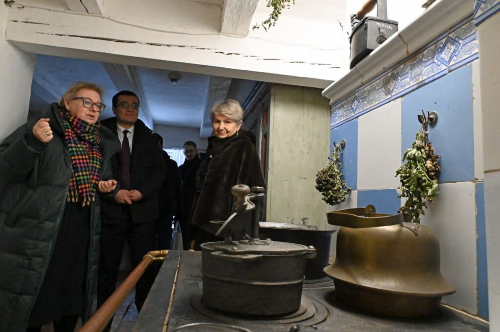 Zwiedzający stojący przy zabytkowym piecu i dawnych naczyniach kuchennych, prezentacja historycznego wyposażenia wnętrza (kliknięcie powiększy zdjęcie).