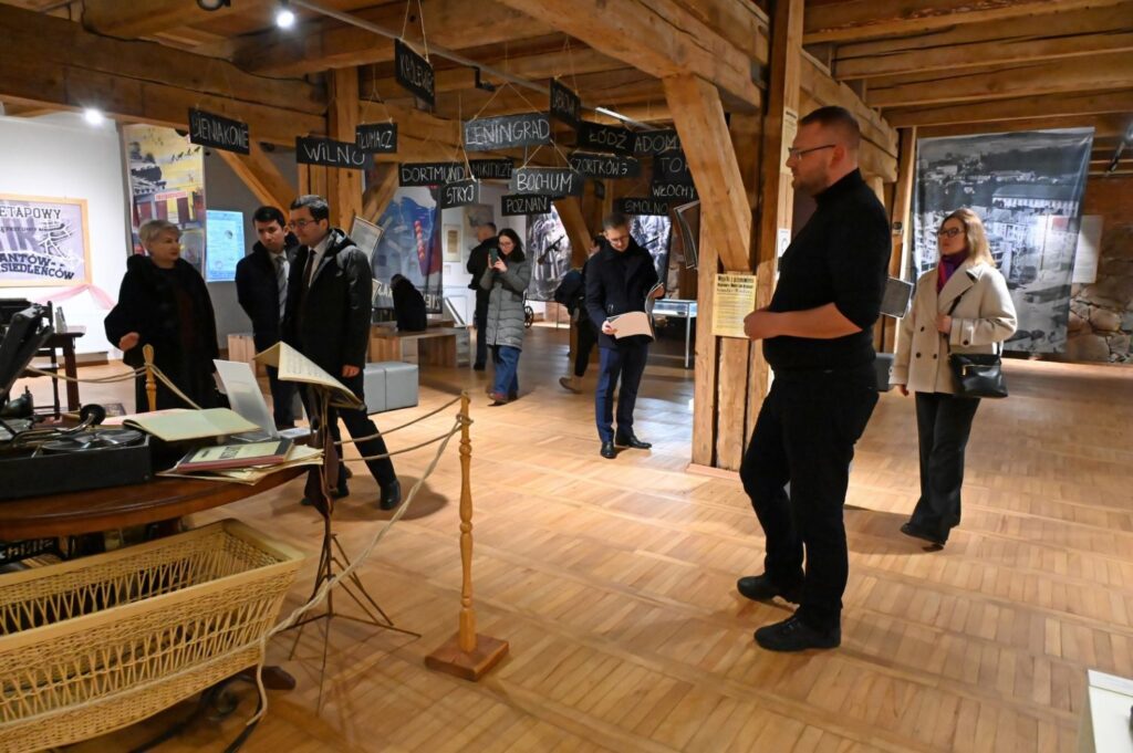 Zwiedzanie wystawy w przestrzeni muzealnej z drewnianą konstrukcją stropu i ekspozycjami historycznymi (kliknięcie powiększy zdjęcie).