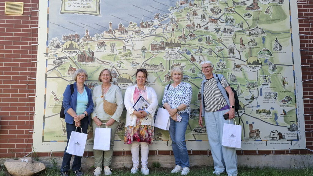 Uczestnicy zwiedzania pozują do wspólnego zdjęcia przed wielkoformatową mapą przedstawiającą region Pomorza (kliknięcie powiększy zdjęcie).
