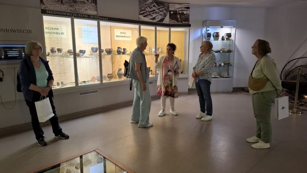Grupa zwiedzających zatrzymuje się w sali wystawowej działu archeologii, słuchając opowieści o prezentowanych eksponatach archeologicznych i historycznych (kliknięcie powiększy zdjęcie).