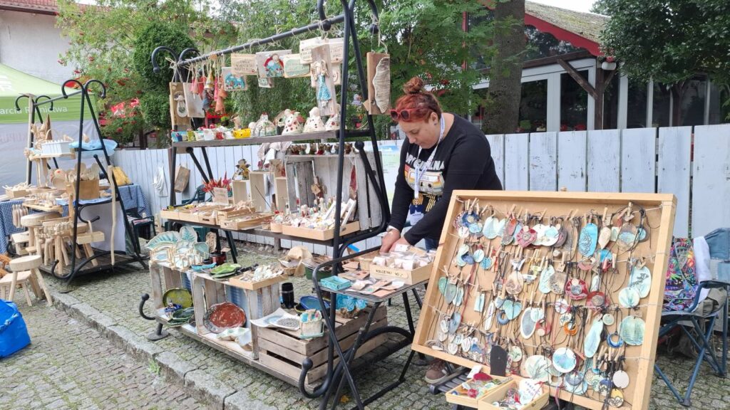 Stoisko z rękodziełem; na stołach i regałach wyeksponowano drewniane przedmioty, biżuterię, ozdoby i drobne wyroby ręcznie wykonane (kliknięcie powiększy zdjęcie).